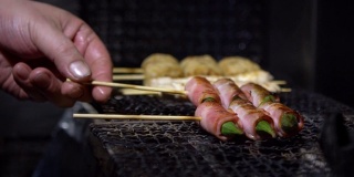 慢镜头小贩在夜市街头用钢烤架烹饪烤肉串。