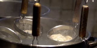 慢镜头日本厨师用滤过的肉汤在火锅上煮饺子。