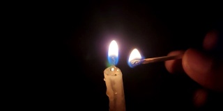 在黑暗的背景中点燃一支蜡烛。慢动作