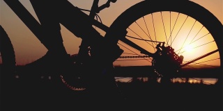 骑自行车的人转动踏板，骑自行车。齿轮系统山地车和车轮旋转在射线日落