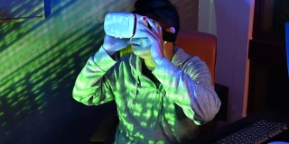 一名亚洲华人男性戴上VR眼镜，在他的家庭办公室自修室里，在他的台式电脑前体验3D虚拟游戏体验