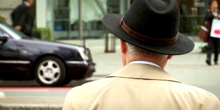 戴着帽子等着过马路的人。一个老人在人行横道上等着