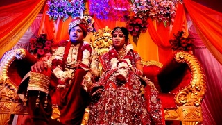 年轻的印度新婚夫妇坐在婚礼台上的豪华沙发上视频素材模板下载
