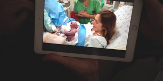 奶奶在打视频电话，看着她的孙子在医院刚出生