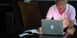 一位老人在客厅用笔记本电脑学习