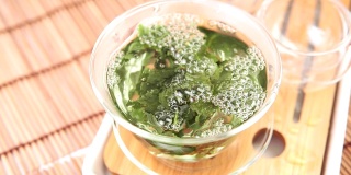 将中国绿茶从玻璃壶倒入小杯子中。近距离选择聚焦