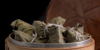 煮粽子-蒸中国粽子在蒸笼，新鲜准备的食物端午节孤立在黑色的背景，接近生活方式。