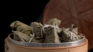 煮粽子-蒸中国粽子在蒸笼，新鲜准备的食物端午节孤立在黑色的背景，接近生活方式。视频素材模板下载