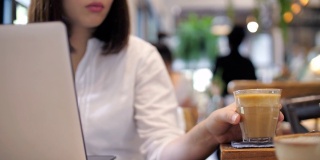 拿着笔记本电脑在咖啡馆喝咖啡的职业女性