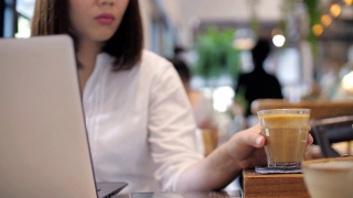拿着笔记本电脑在咖啡馆喝咖啡的职业女性视频素材模板下载