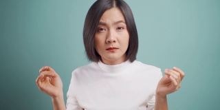 一名亚洲妇女眼睛疼痛，孤立地站在蓝色背景下。卫生保健的概念。4 k的视频。