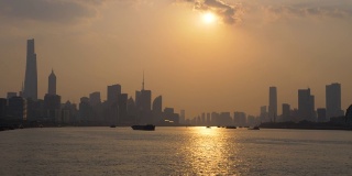 时间流逝镜头在上海城市日落与外滩天际线和黄浦江背景，货船在黄昏的河流上航行，4k镜头，b卷拍摄。