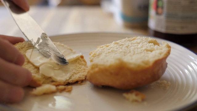 将黄油和果酱涂在刚出炉的烤饼上