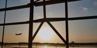日落时分，一架飞机在北京机场的一扇窗户后面起飞