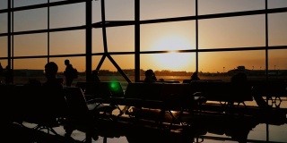 黄昏时分，一个游客站在机场的窗口观看飞机起飞的剪影。旅游理念，人在机场