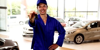白人工人戴着蓝色的墙和帽子在汽车经销商送钥匙车和微笑