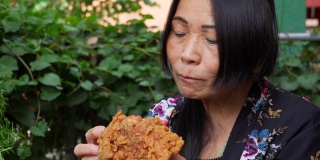 一位亚洲老太太在户外吃炸鸡