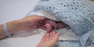 年轻的母亲抚摸着新生婴儿的腿
