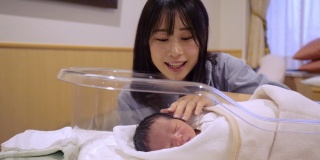 一位年轻的母亲在医院抚摸着她刚出生的婴儿