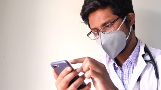 医生戴着口罩在医院里使用智能手机视频素材模板下载
