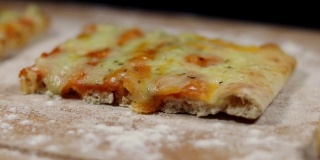 平面包披萨由奶酪在砧板上与面粉在黑色的背景下慢慢旋转