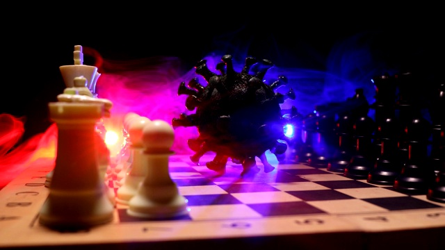 国际象棋棋类游戏的概念策略在Covid - 19全球大流行。棋盘上有雾和背光的大型冠状病毒微型模型。创意艺术品装饰。有选择性的重点