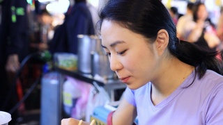 年轻女子在夜市吃臭豆腐视频素材模板下载