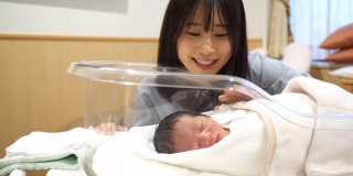 一位年轻的母亲在医院抚摸着她刚出生的婴儿