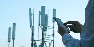 男子手持手机使用5G通信基站塔为背景