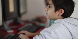 男孩在现代计算机学校的教室里使用台式电脑