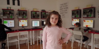 可爱的小女孩站在现代计算机学校的教室里
