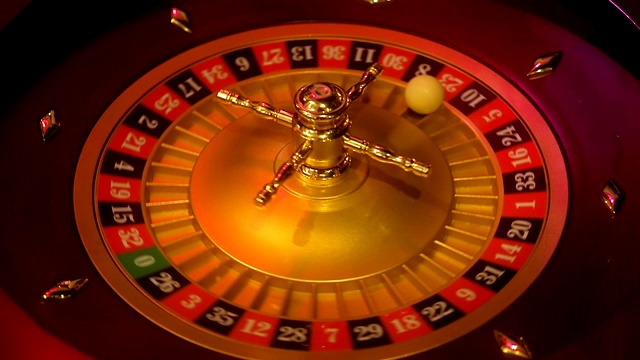 赌场轮盘赌在运动与旋转轮和球。获胜号码23和颜色红色是由轮盘赌轮决定的。低光下的轮盘赌桌布局