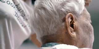冠状病毒隔离:在家里给孙女剪头发的老年妇女