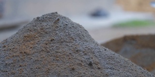 人们用木铲将灰色水泥和黄沙混合