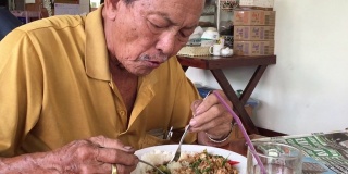 亚洲高级男子吃米饭和炒罗勒与肉末