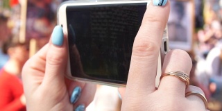 在庆祝胜利日期间，女人的手在手机上做一个视频的特写