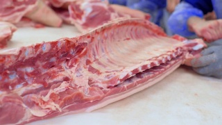 乌克兰顿涅茨克——2018年12月15日——食品工业、肉类加工。屠夫在切割车间的肉类加工厂切猪肉视频素材模板下载