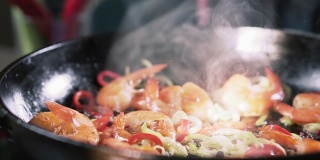 辣椒与炸虾和蔬菜一起落在平底锅里，慢镜头。