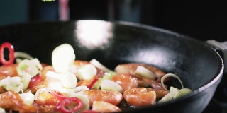 韭菜和辣椒与炸虾一起落在平底锅里，慢动作。