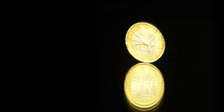 一枚欧元硬币在一面黑色的镜子上旋转