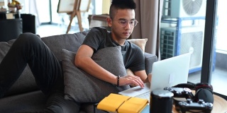 一个亚洲的中国少年男孩在家学习，在客厅用笔记本电脑