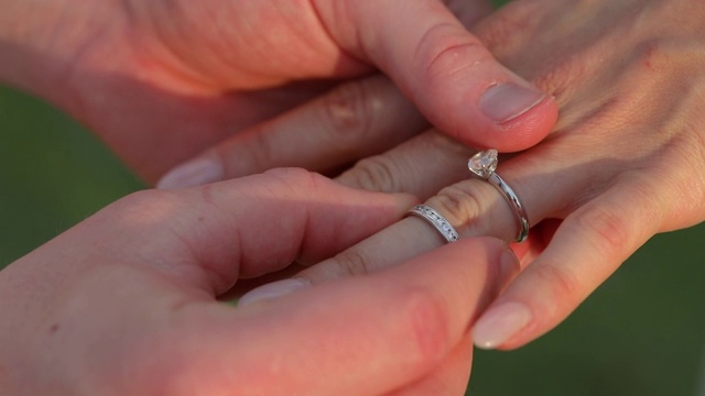 在婚礼上，新郎把戒指戴在新娘的手上。
