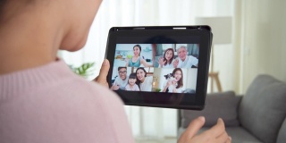 亚洲妇女在家里工作时，在起居室通过视频电话摄像头与家人交谈。自我隔离、社交距离、隔离以保护冠状病毒进入下一个或新的常态。