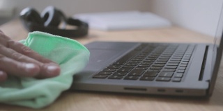 男性手部清洁消毒笔记本电脑键盘，防止灰尘和病毒，保护和消毒冠状病毒