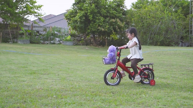 SLOMO女孩在草坪上骑自行车训练