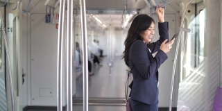 年轻的亚洲女商人在公共交通工具上使用智能手机