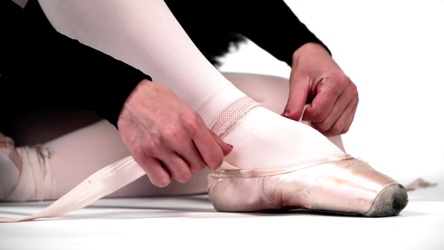 舞蹈演员脚上穿著尖头鞋。芭蕾舞。在白色的背景上。缓慢的运动。
