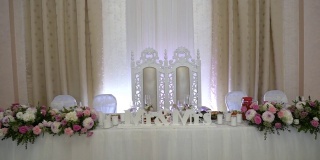 婚礼餐桌上的两个新娘的椅子。桌子上装饰着鲜花。在新娘和新郎的桌子上写着“先生和夫人”