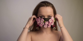 美丽的春姑娘，戴着花面具。春天让我们无法呼吸，花香扑鼻。戴着鲜花和花蕾面具的波特女孩。冠状病毒、面具、大流行。