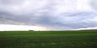 下雨时雨云的快速移动。雨云笼罩着田野。雨前天空的延时视频。